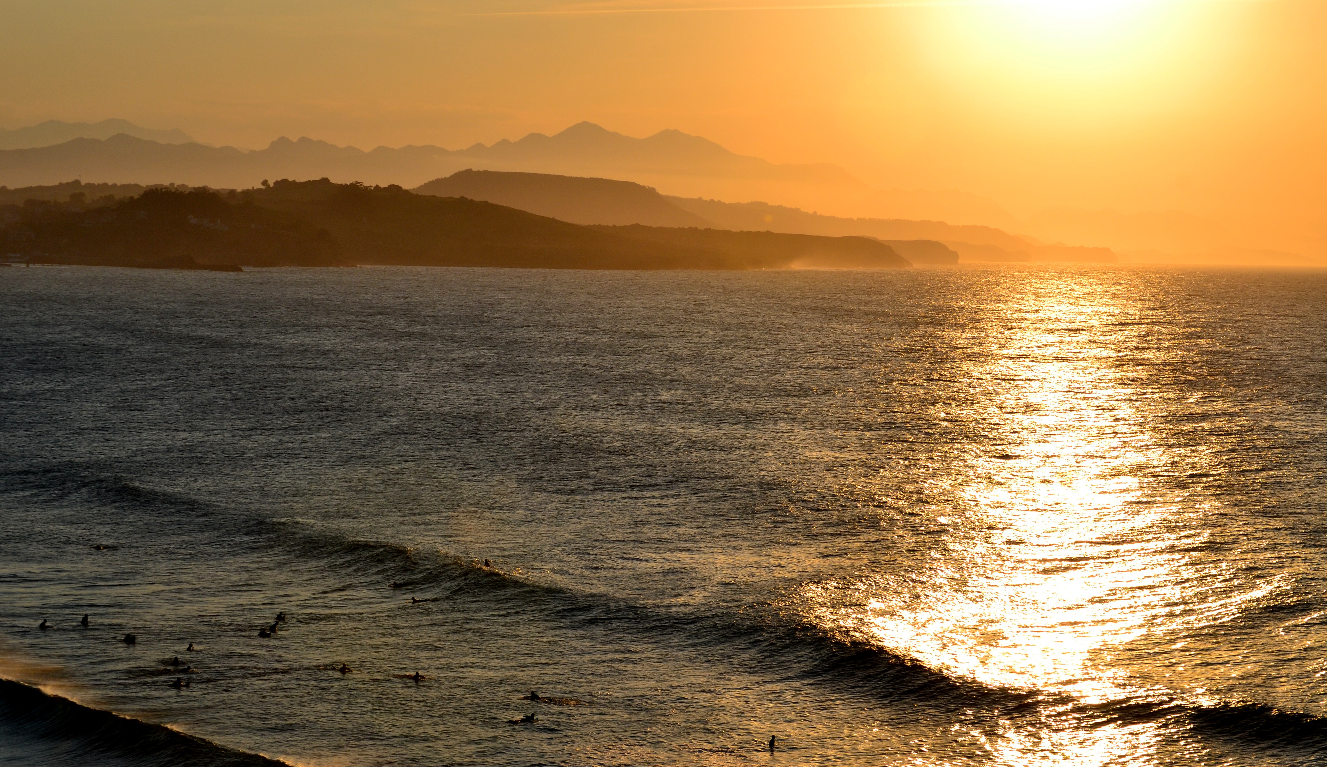 Puesta de sol desde la playa del Cabo de Oyambre. Hay surfistas en el agua